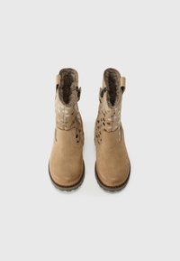 Bottes ankle en suede beige avec une doublure en fourrure texturée, des motifs découpés décoratifs et des zips sur le côté pour un enfilage facile.