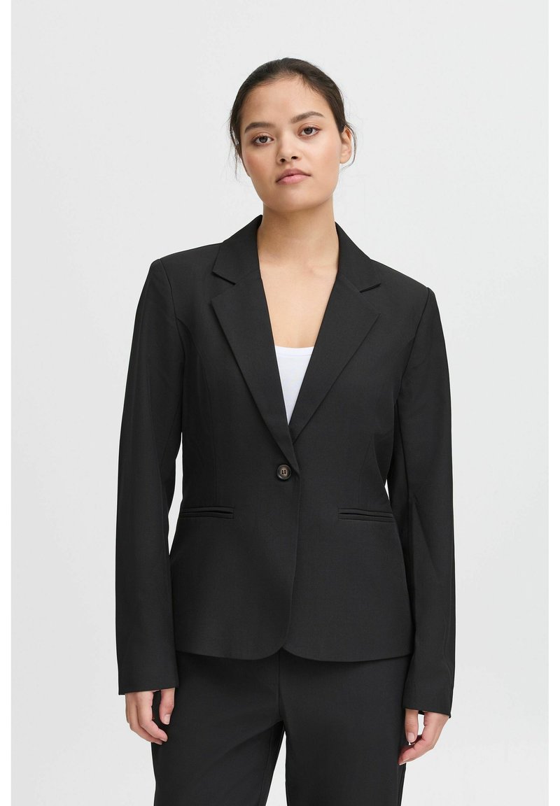 Černý blazer s klopovým límcem, zapínání na jeden knoflík a dvěma předními kapsami. Přiléhavý střih a hladká textura. Spárováno s bílým topem.