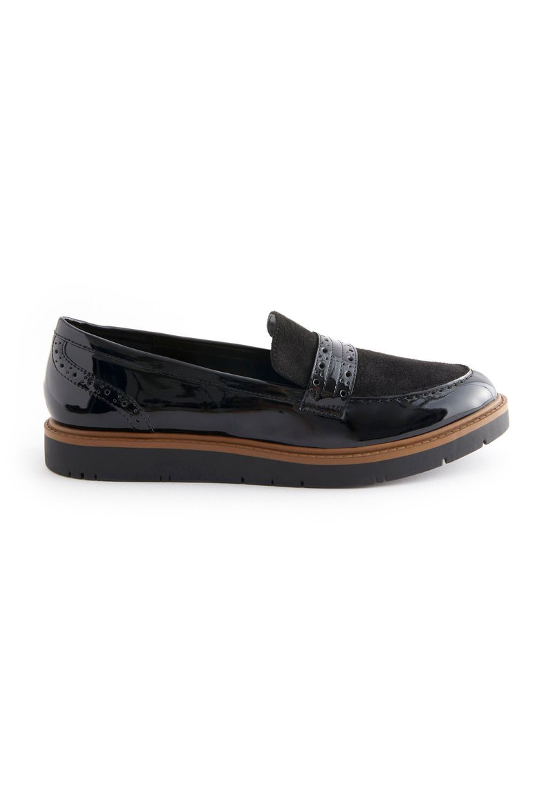Scarpa slip-on in vernice nera con una fascia in camoscio, perforazioni decorative e una suola in gomma marrone a contrasto. Design semplice e arrotondato.