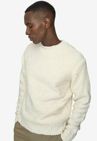 Maglione cremoso con texture, colletto a girocollo e polsini a costine, realizzato in materiale a maglia spessa, caratterizzato da una vestibilità rilassata.