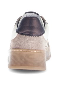 Sneaker met een beige suède bovenkant, een donkerbruine leren hielkap en een gestructureerde rubberen zool. Bevat stikseldetails vlakbij de hiel.
