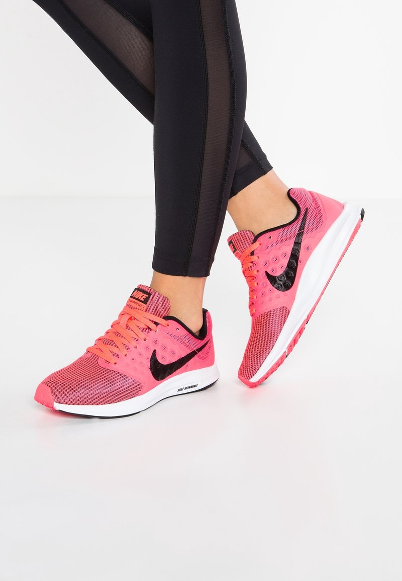 Baskets de course Nike en maille rose vif avec des accents noirs. Le design présente un bout rond, un système de laçage et une semelle texturée.