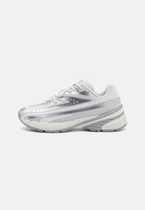 Ahned valged sportlikud kingad, millel on hõbedane võrgust ülemine osa, tekstuuritud detailid ja paks pehmendusega talla tõttu mugavus. Esimene seotud systeem on kaasas.