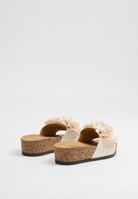 Sandalias de plataforma de corcho con parte superior de suave tela beige y flores decorativas de tela. Diseño de talón abierto y suela texturizada para mayor agarre.