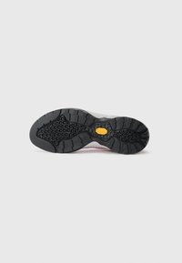 Czarna gumowa podeszwa buta z głębokim bieżnikiem i żółtym logo Vibram na środku, na białym tle.