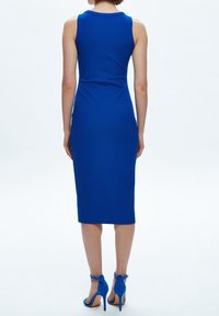 Blå ribbade midiklänning med en figurnära silhuett och utan ärmar. Har en rund halsringning och är kombinerad med matchande blå högklackade skor.