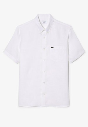Camisa de botones blanca de manga corta en tejido ligero, con un bolsillo en el pecho izquierdo que lleva un pequeño logo verde de Lacoste.