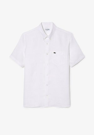 Camisa de botones blanca de manga corta en tejido ligero, con un bolsillo en el pecho izquierdo que lleva un pequeño logo verde de Lacoste.