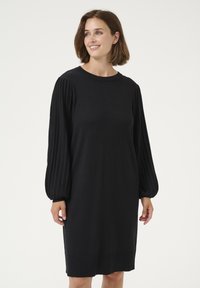 Abito nero con una vestibilità comoda, caratterizzato da maniche lunghe a costine, scollatura a girocollo e orlo dritto. Realizzato in morbido tessuto a maglia.