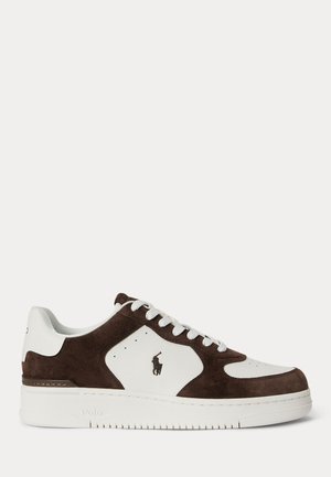 Lavtopsneaker med hvidt læder og mørkebrune ruskindspaneler, hvide snørebånd og et lille sort Polo-logo på siden.