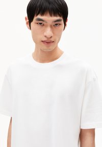 T-shirt en coton blanc avec un col rond et des manches courtes, présentant une texture de tissu lisse et propre et une coupe décontractée.