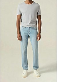 Jeans de mezclilla de un azul claro combinados con una camiseta gris ajustada. Los jeans tienen un diseño de pierna recta y el modelo lleva zapatillas blancas.