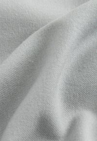 Light gray fabric with a soft, smooth texture and subtle knit pattern, draped to show its flexible and flowy design.