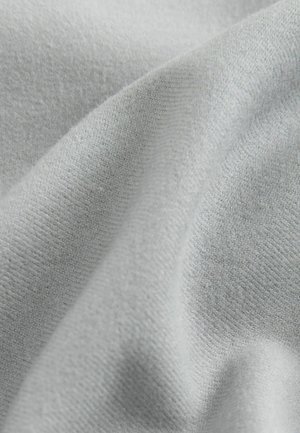 Tissu gris clair avec une texture douce et lisse et un motif de tricot subtil, drapé pour montrer son design flexible et fluide.