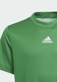 Zelené sportovní tričko vyrobené z prodyšného materiálu, se strukturovaným vzorem, kulatým výstřihem a bílým logem Adidas na hrudi.