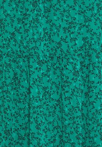 Groene stof met bloemenpatroon en een gestructureerd oppervlak. Bevat kleine zwarte bladeren en bloemontwerpen, met verkrampte secties voor extra textuur.