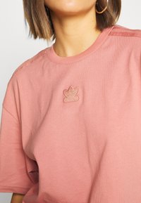 Rosa kortärmad t-shirt i mjukt tyg. Har en liten broderad logotyp på bröstet och texturerade detaljer längs axlarna.