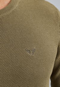 Olivgrüner Strickpullover mit strukturiertem Muster, runder Ausschnitt und gesticktem Logo mit Flügeln auf der Brust.