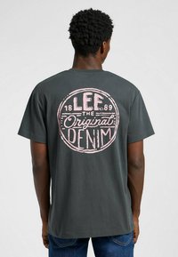 Szara bawełniana koszulka z dużą różową grafiką w kształcie koła na plecach, z napisem "LEE", "Original" oraz "DENIM", okrągły dekolt, krótkie rękawy.