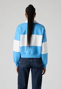 Sudadera corta azul y blanca con mangas largas, con franjas horizontales gruesas y un diseño de cuello clásico.