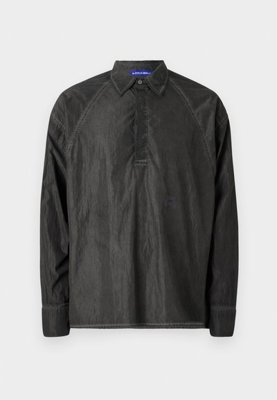 Črna majica z dolgimi rokavi iz lahkotnega materiala, ki ima ovratnik, gumbasto zapenje in diskretno izvezeno oznako na prsih.