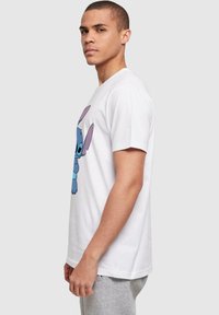 Witte katoenen t-shirt met een afbeelding van een blauwe cartoonfiguur met grote oren, korte mouwen en een klassieke ronde hals.