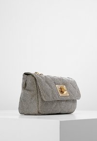 Wytłaczana srebrna torebka z złotym zapięciem, w kształcie prostokąta i z teksturowaną powierzchnią, prezentowana na jasnym tle.