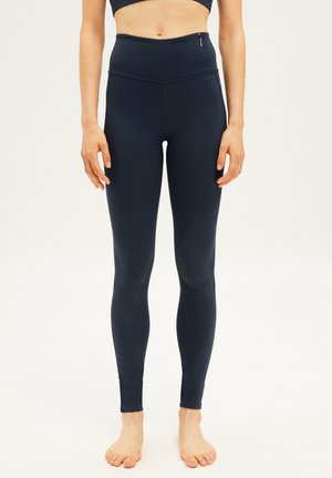 Navy high-waisted leggings made of stretchy fabric, featuring a smooth finish, side zip pocket, and fitted design, suitable for active wear.