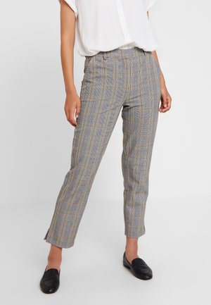 Grijze geruite broek met gele accenten, met een tailored fit, zijzakken en een gladde textuur. Gecombineerd met zwarte instapschoenen.