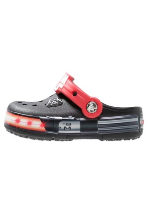 Zueco negro con correa roja ajustable, patrón de estrellas iluminadas en rojo y blanco a lo largo de la suela, y elementos de diseño temáticos de Star Wars.