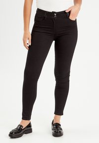 Sorte høj og tætsiddende jeans lavet af strækbart denim, med to frontlommer, knaplukning og en slank pasform ned til anklen.