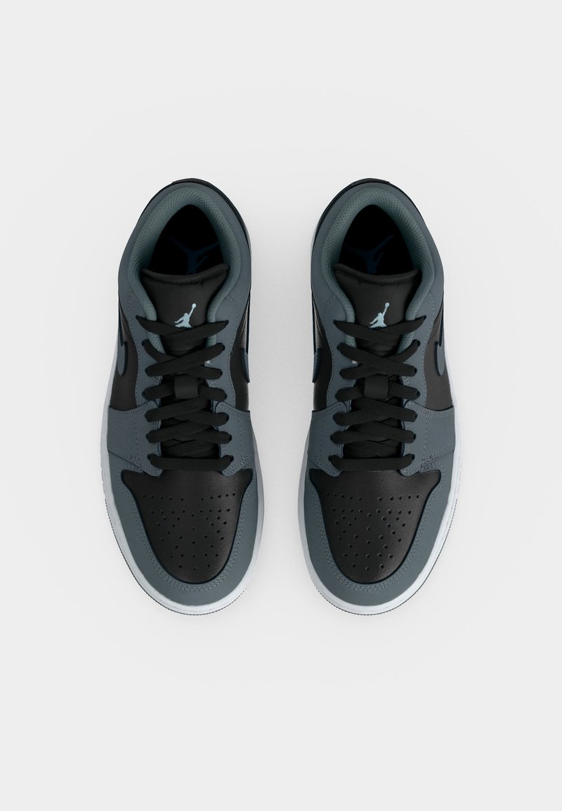 Paar graue und schwarze Nike Air Jordan Sneaker mit schwarzen Schnürsenkeln und perforierten Zehenkästen, von oben auf weißem Hintergrund betrachtet.