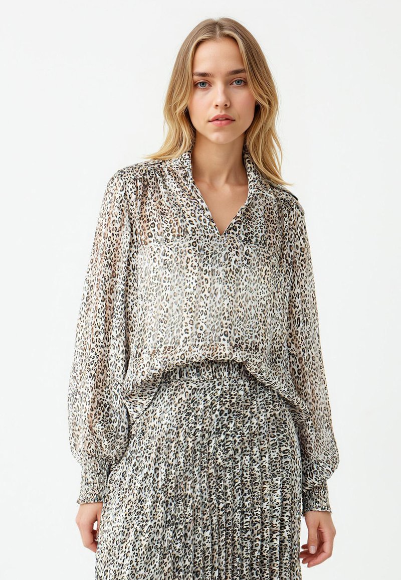 Transparante blouse met een V-hals en lange, opgeblazen mouwen, met een luipaardprint in beige en bruintinten, gecombineerd met een bijpassende rok.