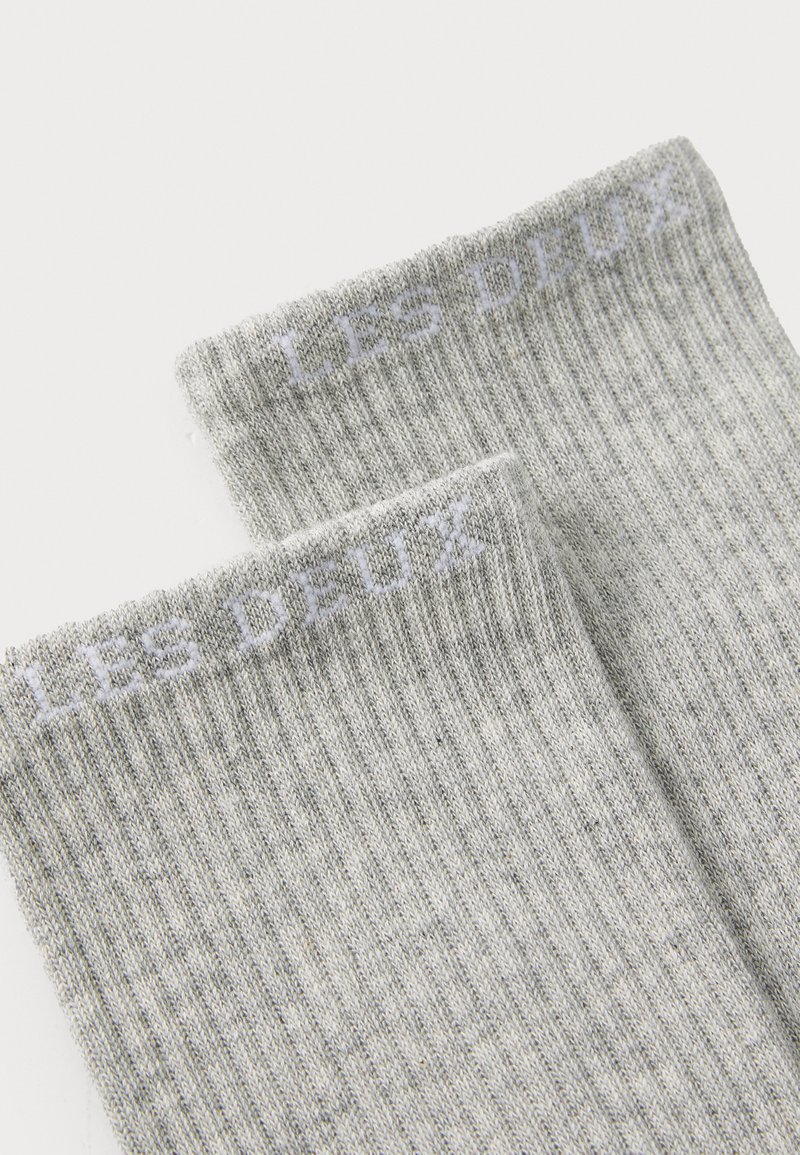 Grå ribbede sokker med et hvidt trykt logo "LES DEUX" øverst. Fremstillet af et blødt, tekstureret materiale med et behageligt design.