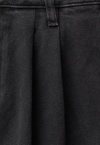 Črno-denim tkanina z teksturirano površino in subtilnim diagonalnim tkanjem, ki prikazuje nabran dizajn okoli pasu.