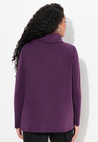 Maglia lunga viola con collo a cowl, realizzata in tessuto morbido, caratterizzata da una vestibilità morbida e dettagli di cucitura discreti all'orlo.