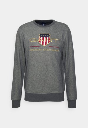 Grijze sweatshirt met lange mouwen, ronde hals, met een geborduurd schildlogo en tekst in rood en geel op de borst.