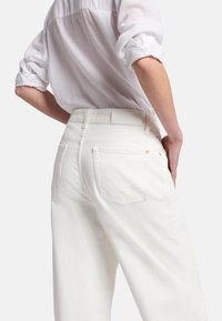 Białe wysokie dżinsy z grubego denimu bawełnianego, z dwiema tylnymi kieszeniami i prostym pasem z małym logo.