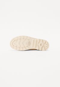 Tălpica adidașilor cu un design din cauciuc texturat de culoare crem, cu un model în zigzag și mici gripuri circulare pentru tracțiune.
