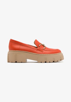 Mocassins en cuir orange avec une semelle plateforme beige épaisse, présentant une sangle décorative et un détail de boucle sur le dessus.