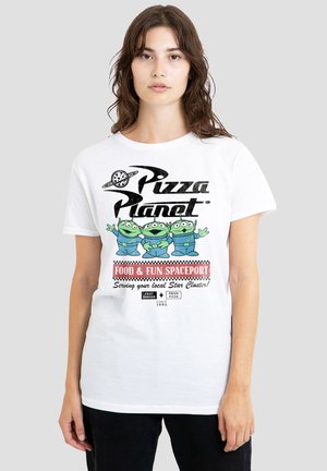 Woman wearing a white T-shirt with green three-eyed aliens and "Pizza Planet Food & Fun Spaceport" text on a plain background.