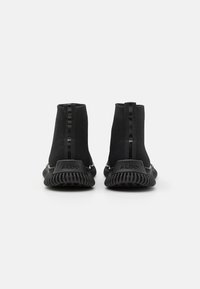 Schwarze High-Top-Sneaker mit einem strukturierten Mesh-Obermaterial, runder Sohle und kontrastierenden Gummielementen. Logo auf der Ferse.