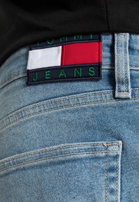 Modré džíny z denimu s nášivkou logo Tommy Jeans, která obsahuje červené, bílé a námořnické sekce přišité na zadním pásu.