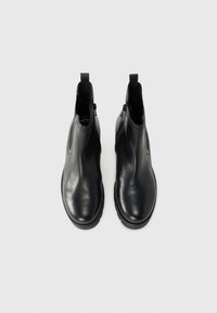 Schwarze Leder-Stiefeletten mit glatter Oberfläche, dezenten Nähten, seitlichen Reißverschlüssen und Zuglaschen an der Rückseite für ein einfaches An- und Ausziehen.
