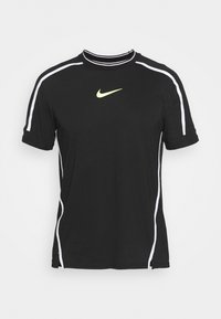 Musta Nike-t-paita lyhyillä hihoilla, jossa on valkoinen korostusraita ja pieni keltainen logo rinnassa. Valmistettu pehmeästä ja hengittävästä materiaalista.