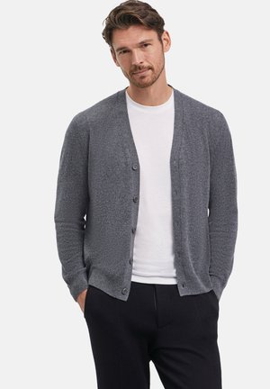 Grauer Cardigan aus strukturiertem Strickmaterial, mit V-Ausschnitt, Knopfverschluss und gerippten Bündchen, kombiniert mit einem weißen T-Shirt.