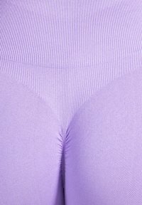 Leggings ajustados y acanalados en lavanda claro con textura suave. Cuentan con una cintura de tiro medio y un sutil fruncido en la parte trasera.