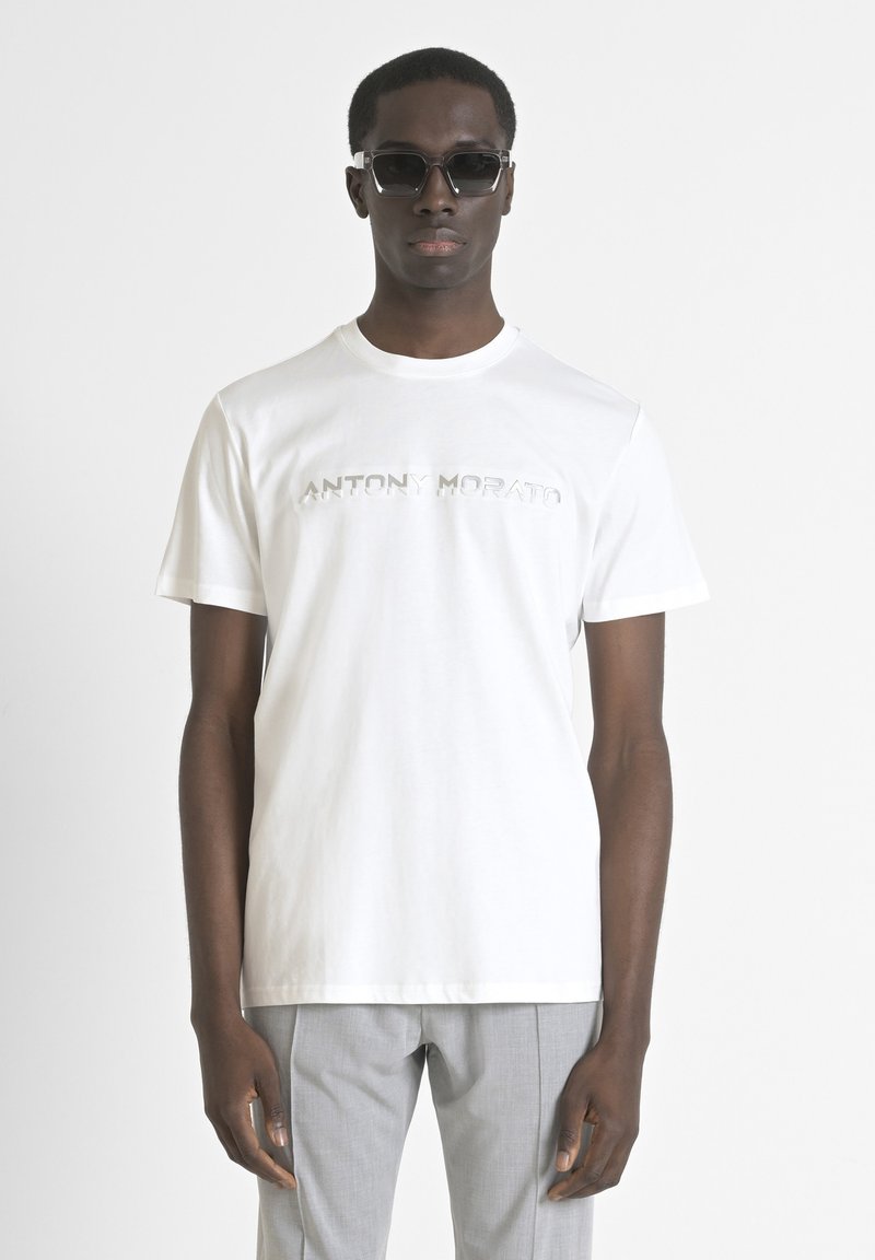 Witte katoenen t-shirt met een reliëf "ANTONY MORATO" logo. Korte mouwen en een klassieke ronde halslijn. Gepaarde met lichtgrijze broeken.