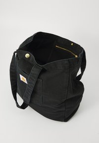 Borsa tote nera in tela con finitura testurizzata, ampio scomparto principale, tasca con zip dorata e una toppa anteriore con logo.