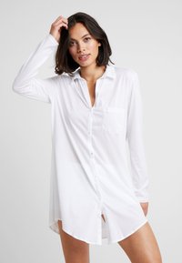Abito camicia bianco a maniche lunghe con chiusura a bottoni, colletto a punta, tasca singola sul petto e spacco laterale, realizzato in tessuto leggero.